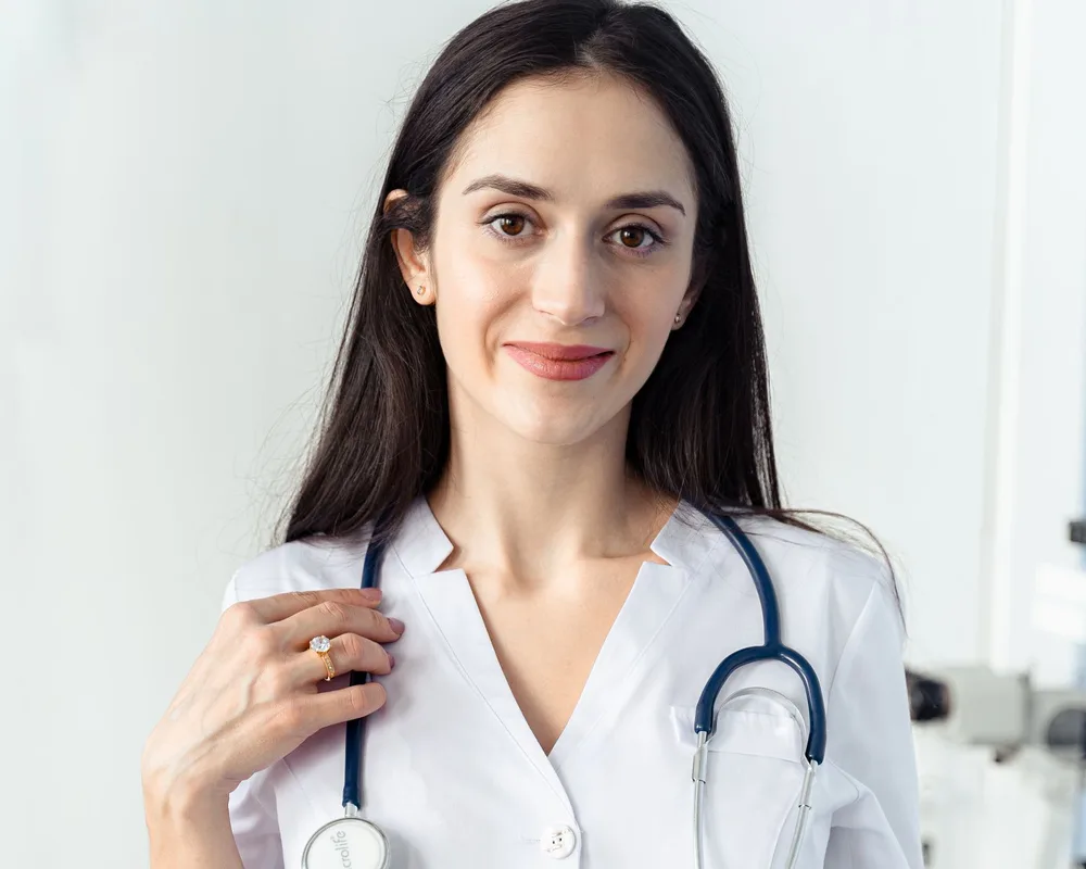 A smiling clinician in a white coat with a stethoscope.